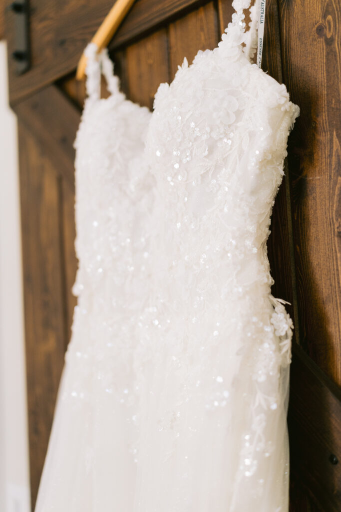 brides wedding dress hanging on barn doors