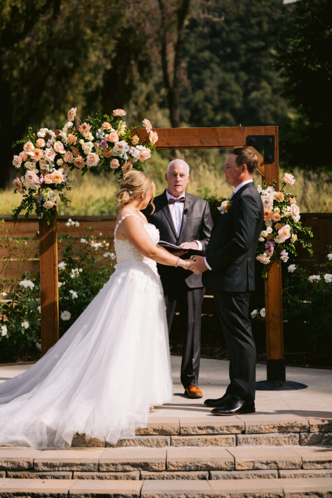 officiant speaking as bride and groom hold hands at ceremony