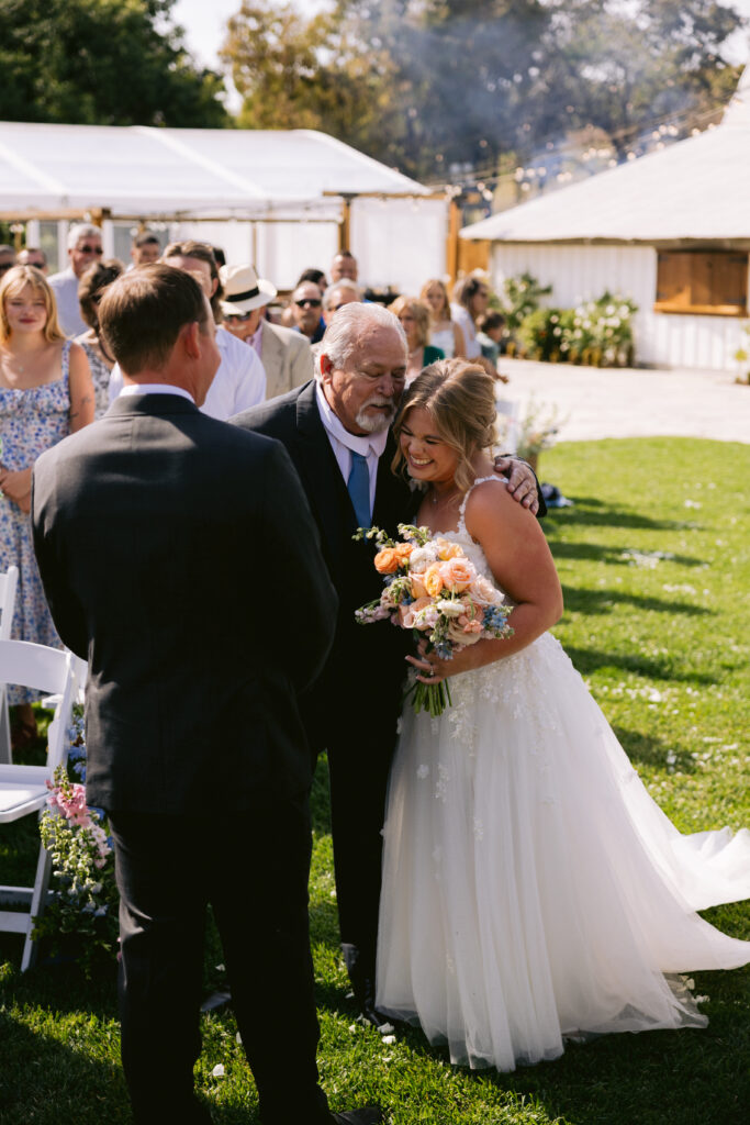 bride hugs father as he walks her down the aisle
